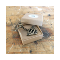 Handgefertigter V8 Schlüsselanhänger im Flammen‑Design aus Messing in Geschenkbox auf Werkbank – ideales Geschenk für Hot‑Rod‑Fans, Schrauber und Pickup‑Enthusiasten.
